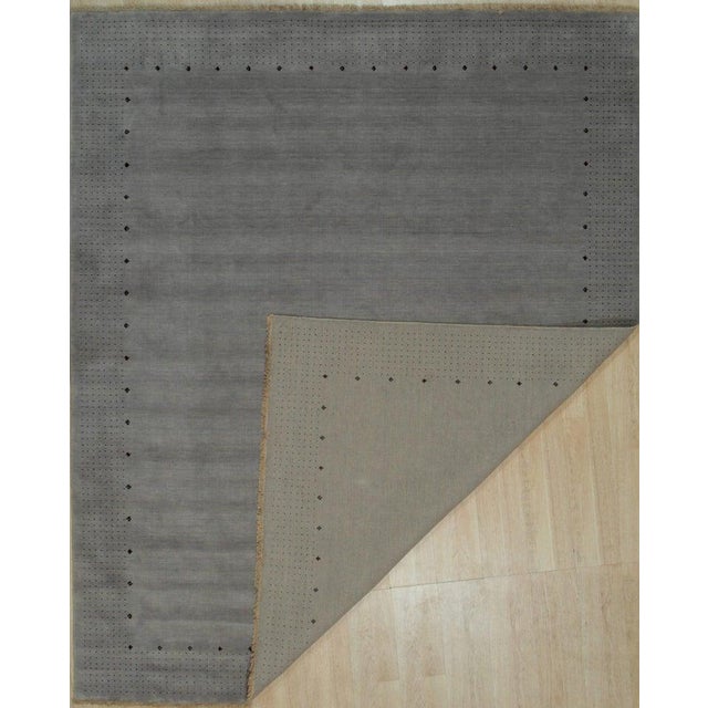 This hand knotted pile rug features a primary gray color and is constructed from high-quality wool. Sourced from India as...