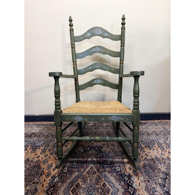 Beautiful Dutch vintage ladderback rocking chair in an elegant off-green finish with parcel gilt accents and hand-painted...