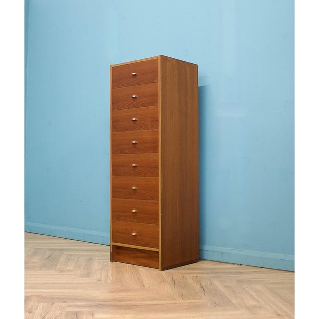 A Danish tallboy chest of drawers by SM Quality, made in Denmark and dating to the 1970s. Finished in teak veneer with a...