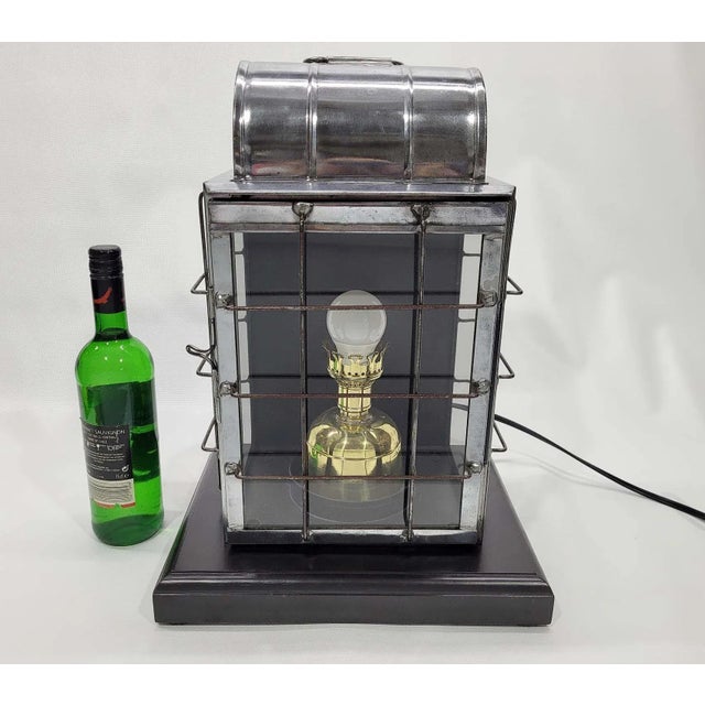 Ships lantern by the National Marine Lamp Company. Polished steel case with protective wire cage. The brass burner has...