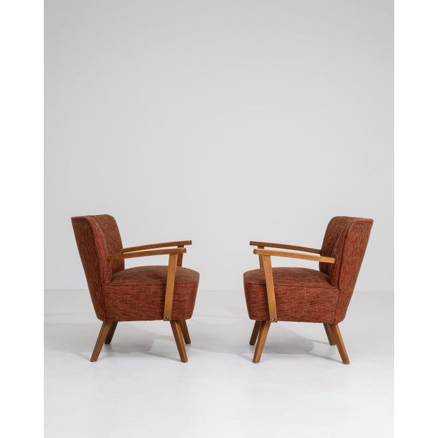A pair of 20th century mid-century modern armchairs featuring wooden frames with upholstered seats and backs. The design...