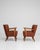 A pair of 20th century mid-century modern armchairs featuring wooden frames with upholstered seats and backs. The design...