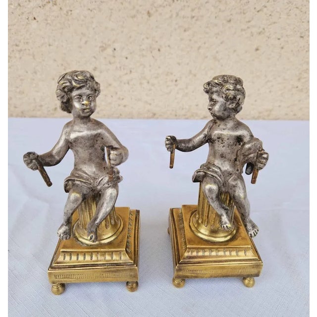 Pair of silver-plated bronze putti seated on ormolu fluted truncated columns, standing on pedestals with ball feet. Good...