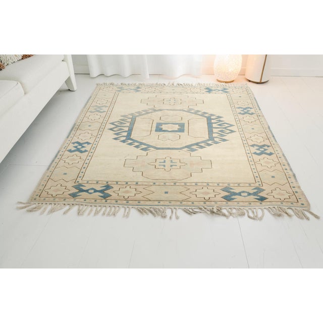This is a vintage Turkish Oushak rug from the Mid 20th Century. The piece was hand-knotted.
