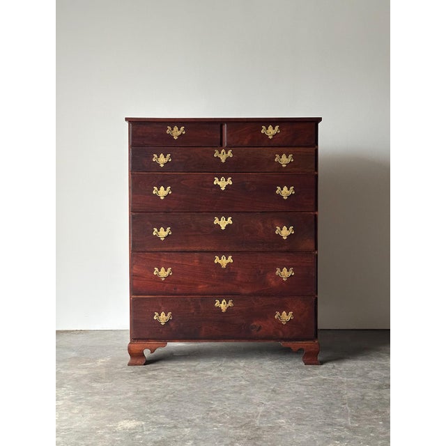 This tall walnut chest rises through seven graduated drawers, two short up top, five long below, each fitted with pierced...