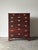 This tall walnut chest rises through seven graduated drawers, two short up top, five long below, each fitted with pierced...
