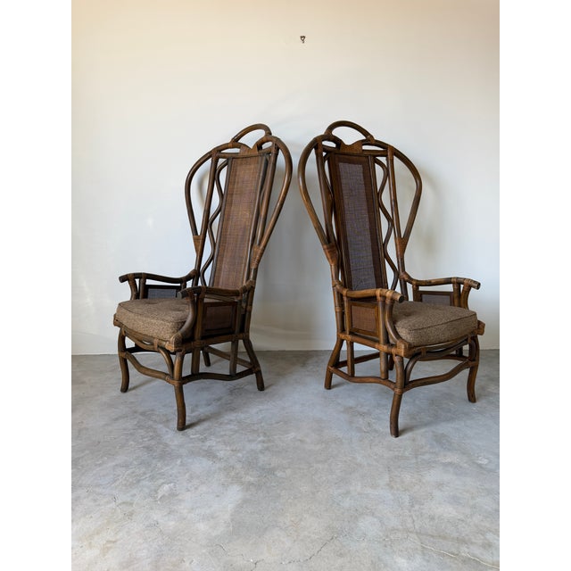 Beautiful vintage pair of high back arm chairs featuring bent rattan frames, woven wicker panels, decorative wrapped...