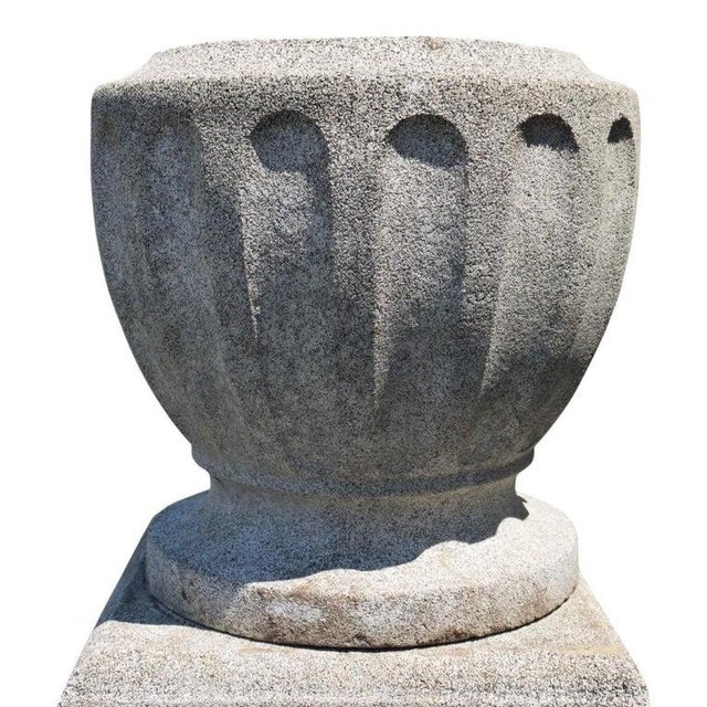 A substantial garden urn, crafted from cast hardstone presenting a natural speckled grey texture. The design features a...