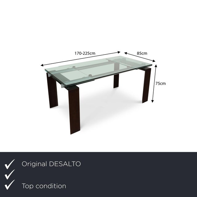 The Stilt dining table from Desalto consists of a rectangular glass top and stands on black metal feet. It is...