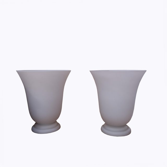 A pair of goblet-shaped lamps with narrow, stepped bases and wide openings that project light upwards. Made of frosted...