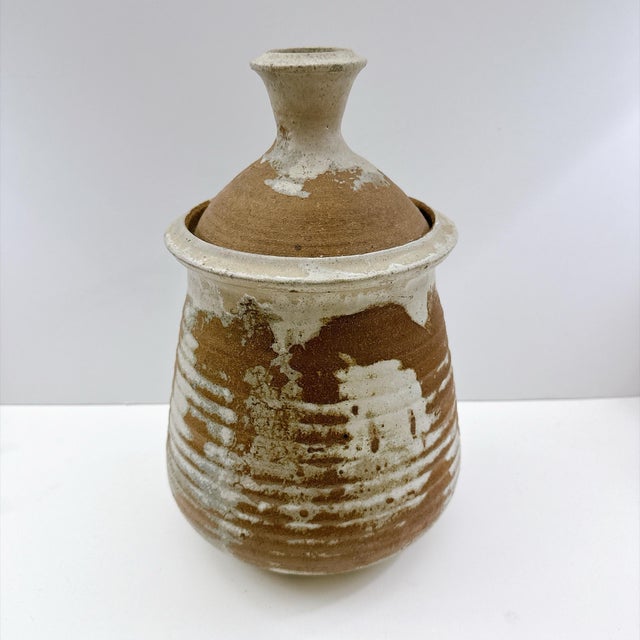 Beautiful vintage handmade studio pottery lidded vessel featuring a warm earthy brown clay body with an expressive cream...