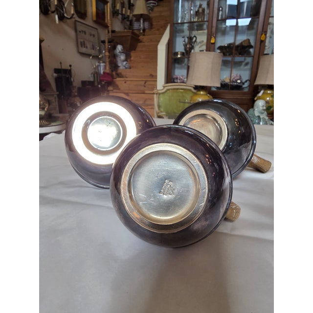 Collection of three rounded teapots with woven wicker like handle covers. Two larger ones and a third smaller one.