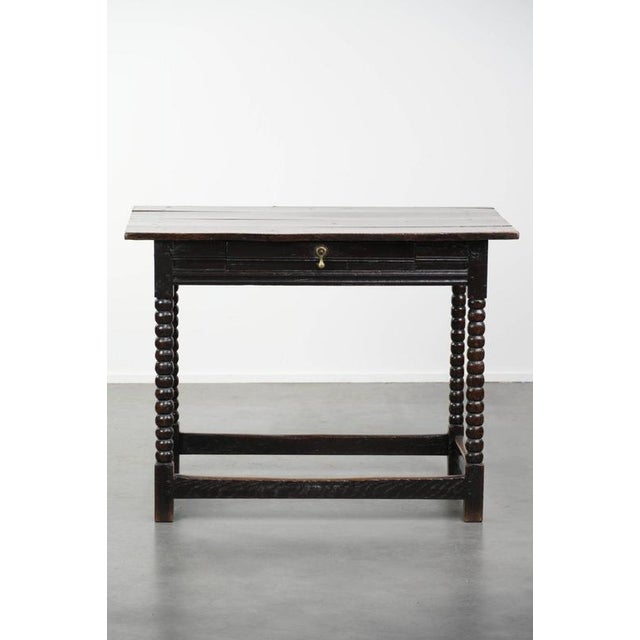 This uniquely beautiful antique English oak side table dates from the 18th century and features a practical drawer and...
