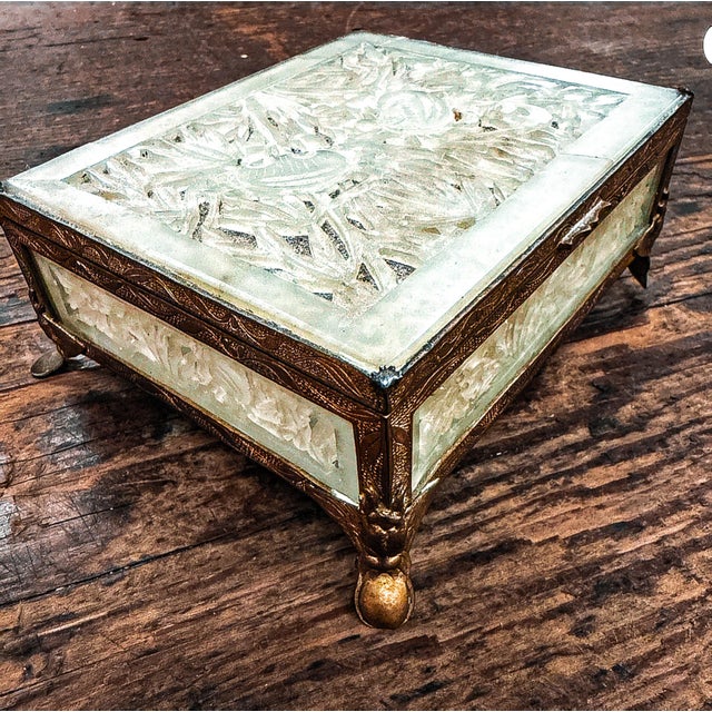 A vintage Chinese jewelry box made of intricately carved jade panels, showcasing intricate floral designs, framed in...