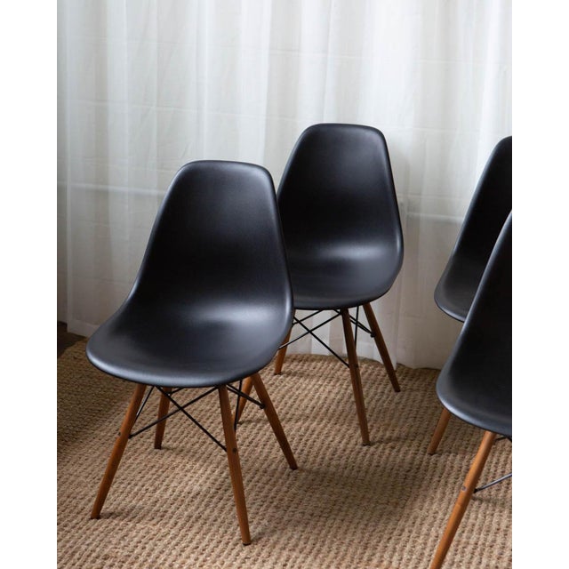 A classic set of four Design Within Reach Eames molded plastic dining chairs with warm wood dowel legs. Timeless mid-...