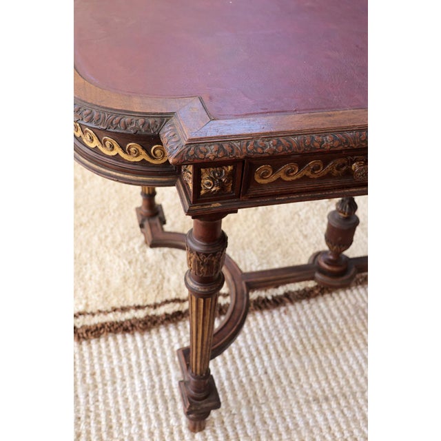 This hand-carved Louis XVI-style bureau plat features gold-painted details throughout and fluted, tapered legs. The red...