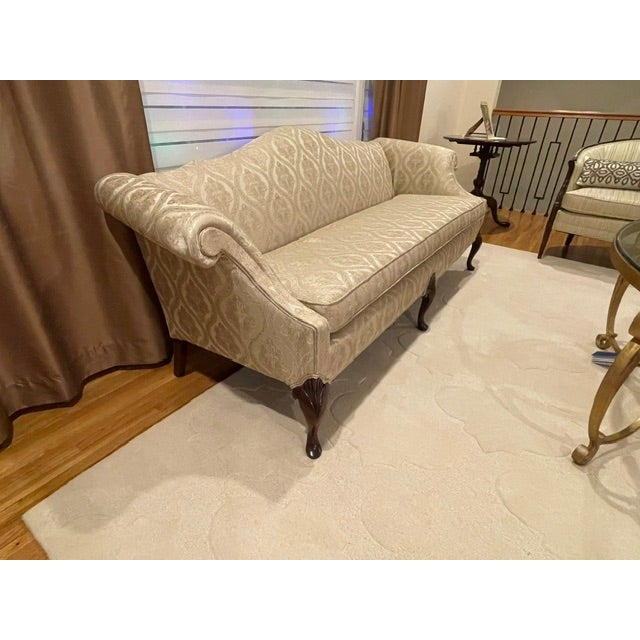 An elegant 18th-century revival Chippendale camelback sofa featuring a gracefully arched crest rail, flared outscrolled...