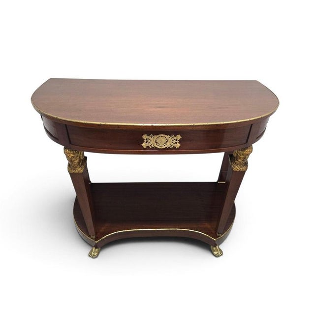 An elegant and highly decorative French Empire demilune console table, distinguished by its refined proportions and rich...