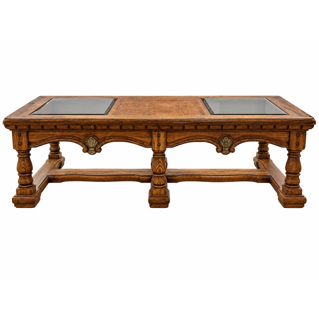 A vintage Mediterranean Revival coffee table featuring a warm brown wood finish, geometric parquet-pattern center panel,...