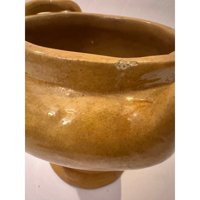 A vintage ceramic vessel with a classic urn-like silhouette, a rounded, footed base tapering up into a wide, flared body....