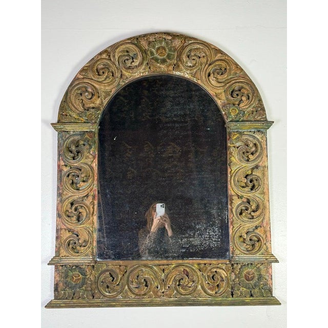 This striking antique arch-top mirror features a richly carved giltwood frame adorned with bold scrolling foliate motifs...