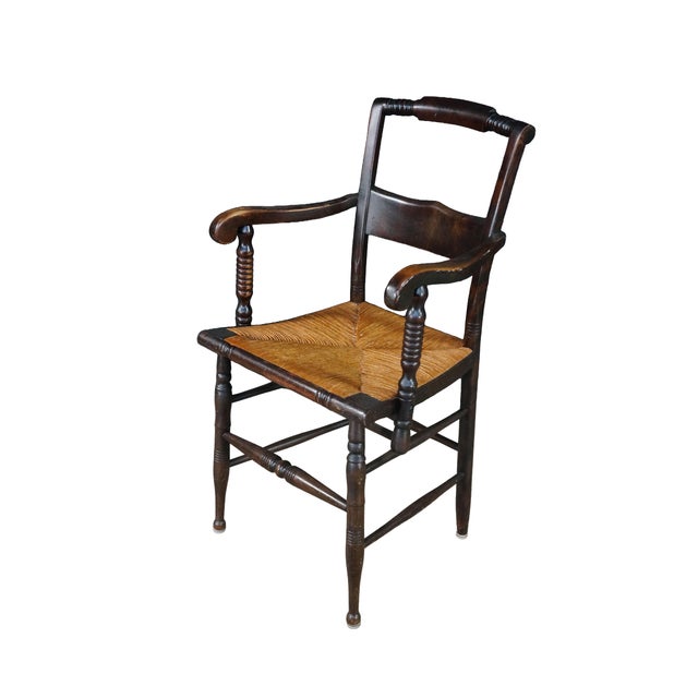 Antique Early American Federal or Hitchcock-style captain's armchair dating back to the 19th century. Crafted from a dark-...