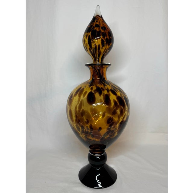 Large tortoise shell glass pedestal jar with large bulb teardrop stopper. Unmarked. 21” height including stopper. 8” at...