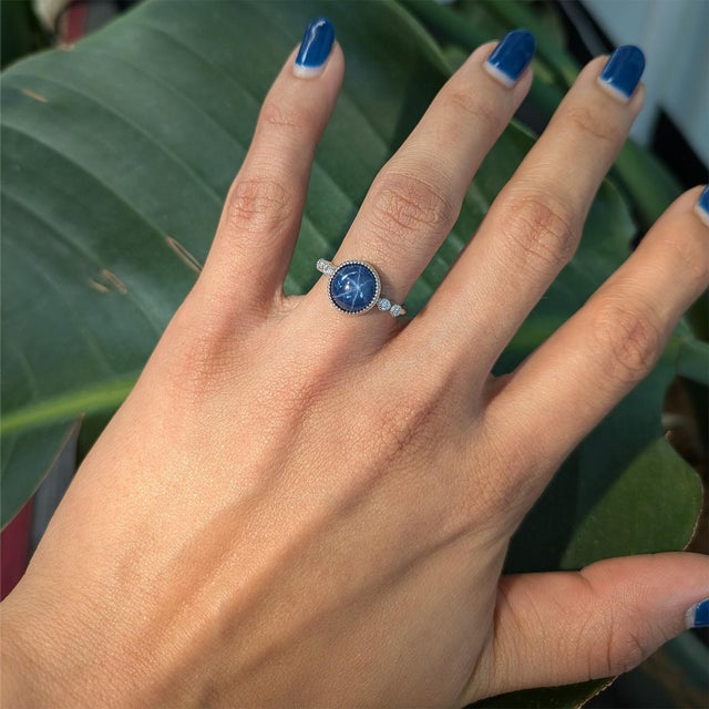 A 4.1ct round 9mm star sapphire ring set in solid 14K gold, accented with natural diamonds for added brilliance. Elegant...