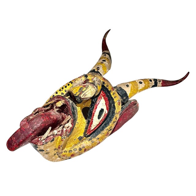This powerful and visually striking mask is hand carved from wood and richly painted in vivid reds, greens, yellows, and...