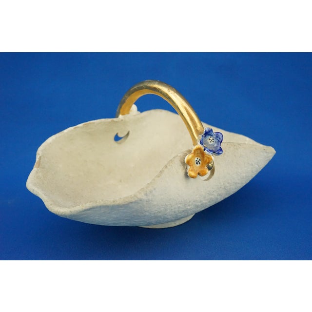 A charming small glazed ceramic basket with a handle finished in pure gold and small hand-applied and sculpted flowers in...