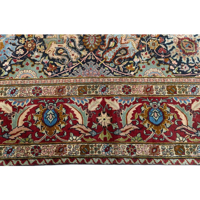 An early 20th century size-adjusted antique Persian Tabriz carpet in which the dark blue field is contrasted with a bold...