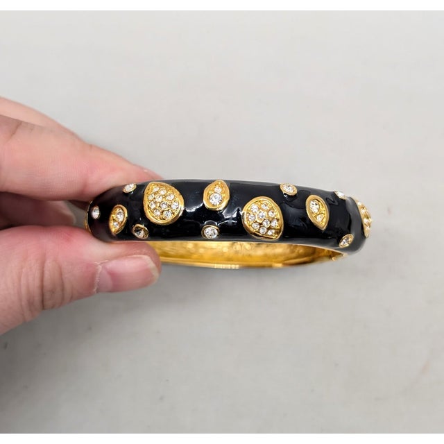 1990s goldtone black enamel with round clear rhinestones hinged cuff bracelet with box clasp. Marked "Napier" in script....