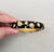 1990s goldtone black enamel with round clear rhinestones hinged cuff bracelet with box clasp. Marked "Napier" in script....
