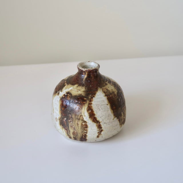 Vintage handmade studio pottery bud vase featuring a sculptural rounded bottle form with a narrow neck and richly layered...