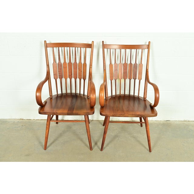 A gorgeous pair of Mid-Century Modern sculpted walnut armchairs or dining captain chairs In the manner of George Nakashima...