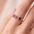 A bold, contemporary open-cuff ring featuring two vivid purple amethysts — an oval-cut stone paired with a round-cut stone...