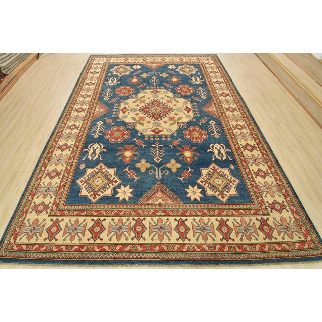 This traditional tribal geometric Caucasian Kazak rug is hand-knotted with an all-wool pile on a cotton foundation. This...