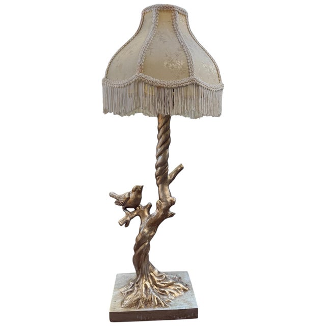 Striking vintage sculptural table lamp featuring a detailed bird perched on a naturalistic tree trunk, paired with an...