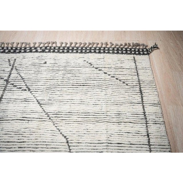This hand-knotted pile rug features a primary color palette of ivory, beige, cream, and white. Crafted from natural wool,...