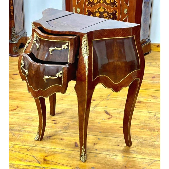 This elegant French-style two-drawer cabinet features a richly finished wood construction with a graceful bombe silhouette...
