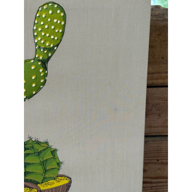 A playful and vibrant textile wall hanging by Ed Tillary, featuring a charming arrangement of potted cacti in saturated...