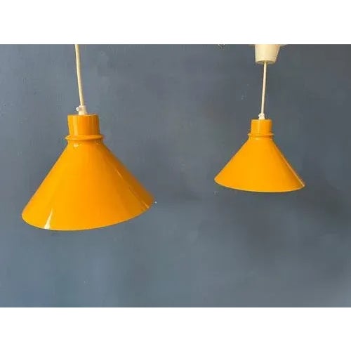 Very tasteful set of two yellow mid century metal pendant lamps. The lights look great together as a set. The ocre yellow...