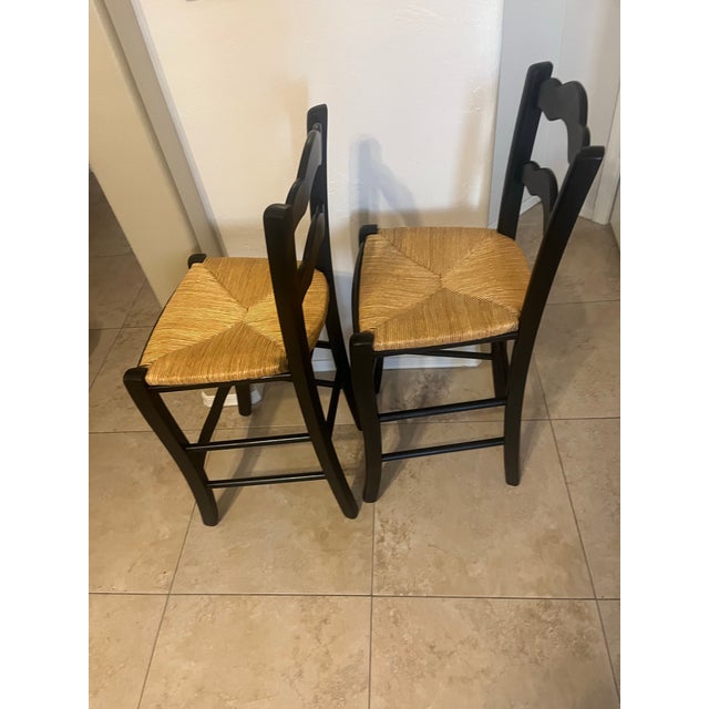 French Country-style ladder-back bar or counter stools featuring a classic wavy double-slat backrest and a hand-woven...