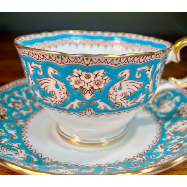 Brown scrolls and griffins on turquoise with gold trim. Cup- 4.5”L x 3.75”W. 2.5”H Saucer- 5.5”L