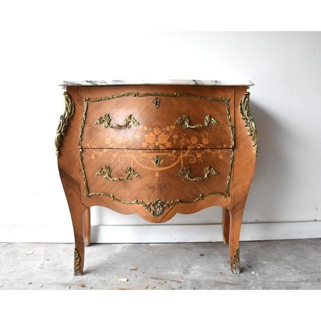 An antique, late 19th-eary 20th century dresser, commode, or chest of drawers in the French Louis XV style with a curved...