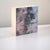 This intimate oil painting on cradled panel features a delicate interplay between a serene face and blooming floral...