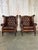 An elegant pair of classic Chesterfield-style wingback armchairs upholstered in rich deep brown leather with beautifully...