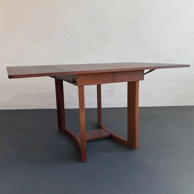 This gorgeous Mid-Century Modern walnut gate-fold, drop-leaf dining table was designed by British designer T.H. Robsjohn-...