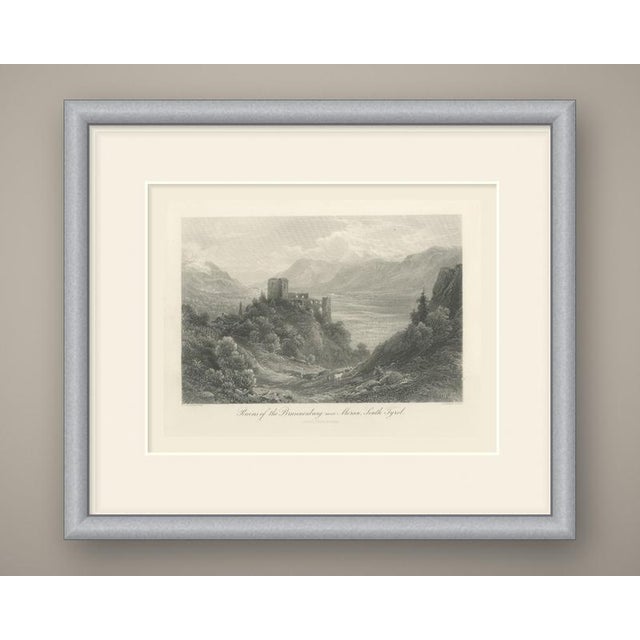 A wide alpine view from a wooded hillside above the adige valley. On a rocky spur at left stand the broken walls and...
