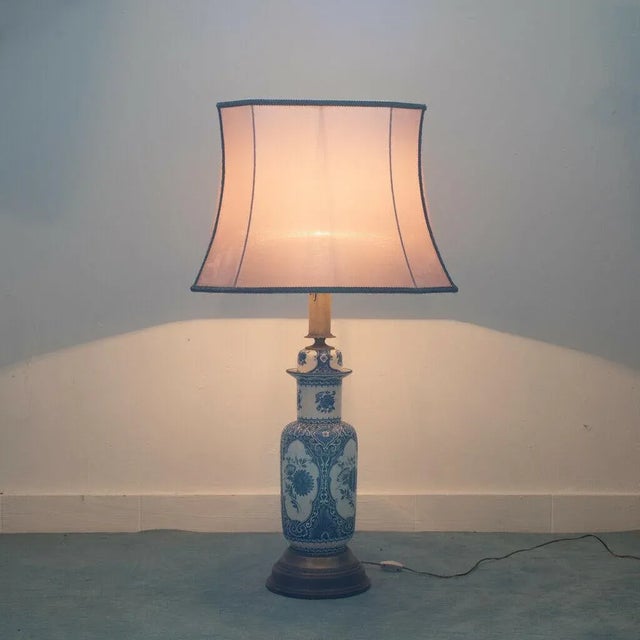 Table lamp single lamp.Ceramic with blue floral decorations, wooden base and brass inserts.Lampshade in pink silk.The...